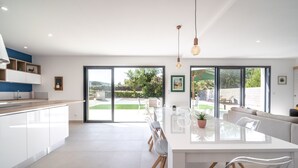 A modern kitchen with a large island, white cabinetry, and a view of the outdoors. - Holiday Home Beaufort With Private Pool (Beaufort)