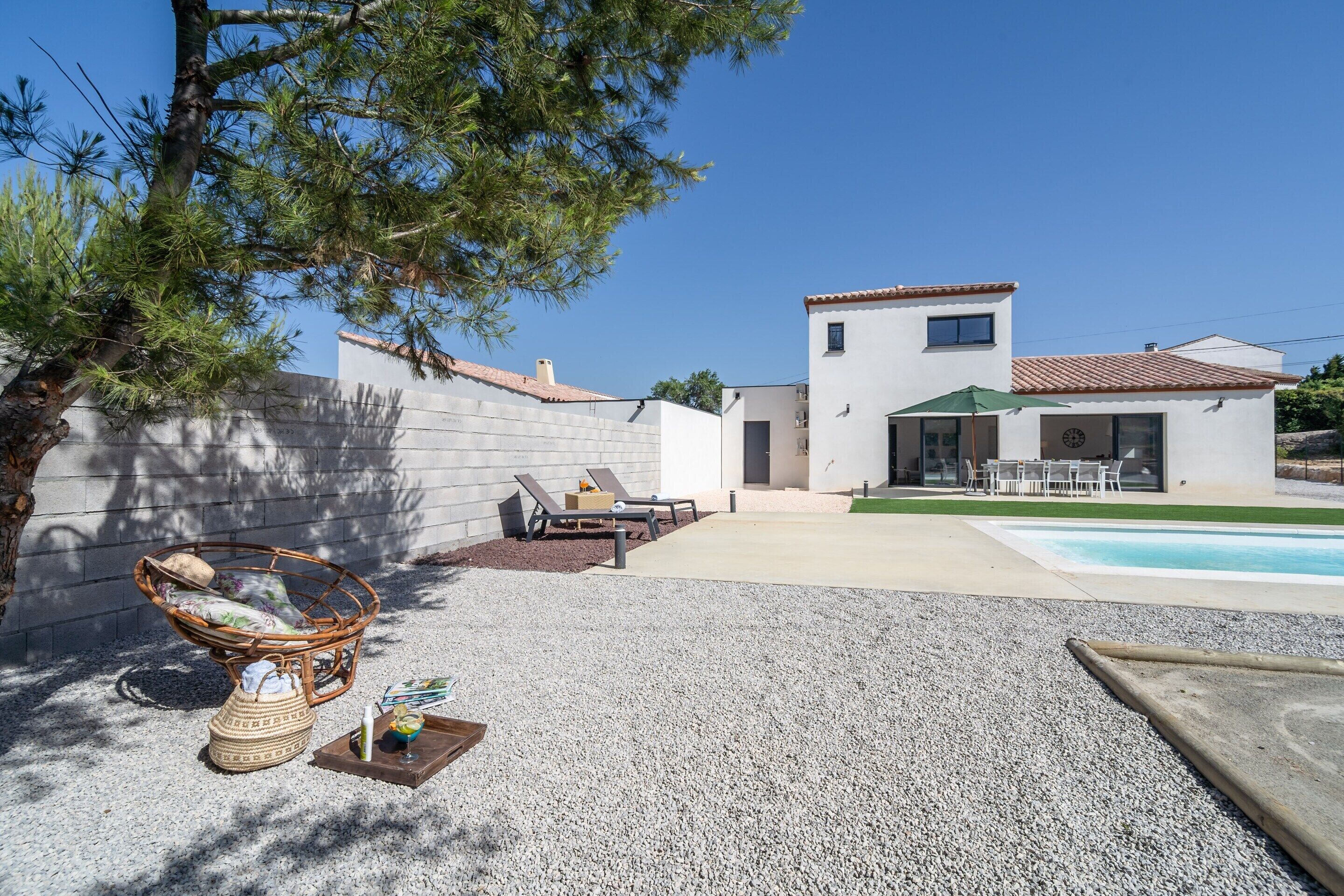 Une maison moderne dotée d’une piscine, d’un espace salon extérieur et d’une pelouse bien entretenue.