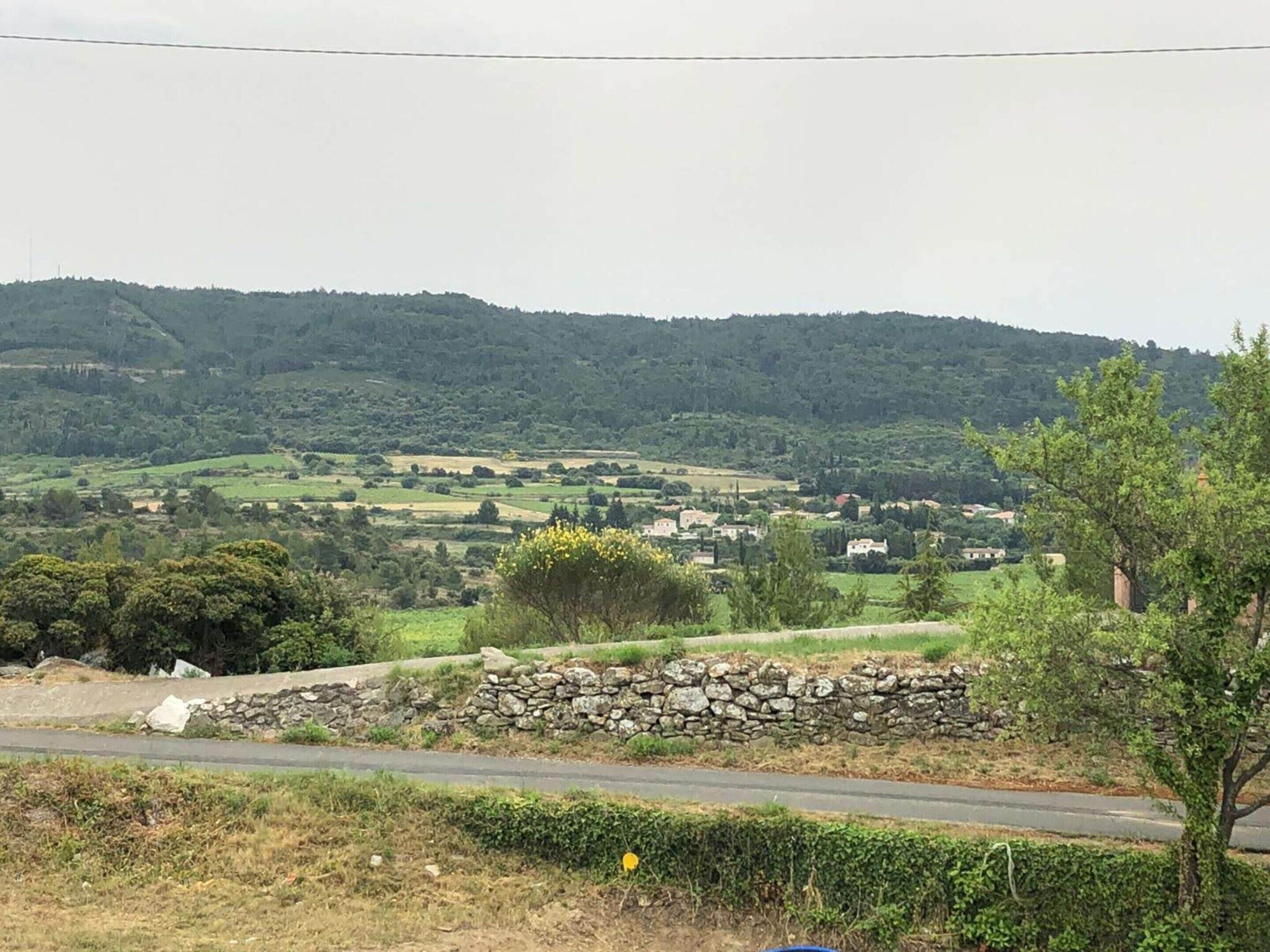 A rural landscape with a stone wall, a road, and scattered houses.