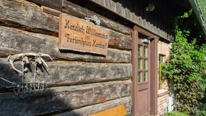 A rustic wooden building with a sign welcoming visitors to a traditional inn. - Holiday Home in the Forest (Schmogrow)