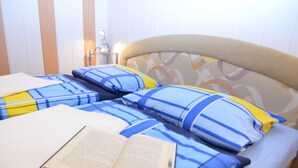 A bed with blue and yellow striped bedding, a bedside lamp, and an open book on the bed. - Ferienhaus, Wernigerode (Wernigerode)
