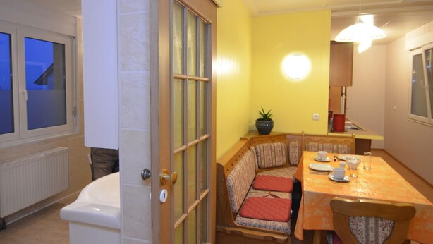 A compact kitchen with a dining area, a built-in bench with cushions, and a potted plant. - Ferienhaus, Wernigerode (Wernigerode)