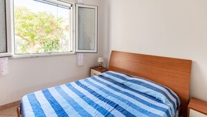 A bedroom with a bed, a nightstand, a window, and a view of greenery outside. - Simplistic Holiday Home in Sciacca near Horse Riding (Sciacca)