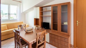 A dining area with a wooden table and chairs, a yellow sofa, and a cabinet with glass doors. - Simplistic Holiday Home in Sciacca near Horse Riding (Sciacca)