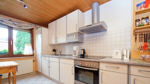 A modern kitchen with white cabinets, a stainless steel range hood, and a window with a view of greenery. - Amazing Apartment in Großalmerode near Cross Country Skiing (Grossalmerode)