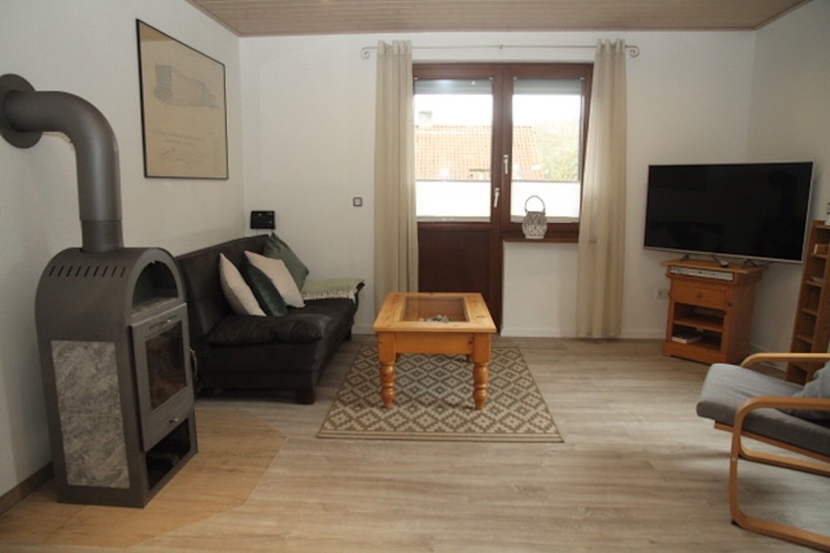 A living room with a fireplace, a sofa, a TV, and a window with curtains.