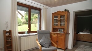 A room with a wooden chair, a cabinet with glass doors, a radiator, and a window with a view of greenery. - Amazing Apartment in Großalmerode near Cross Country Skiing (Grossalmerode)