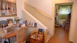 Una sala de estar acogedora con comedor, que incluye una escalera, una estantería y un cuadro en la pared.