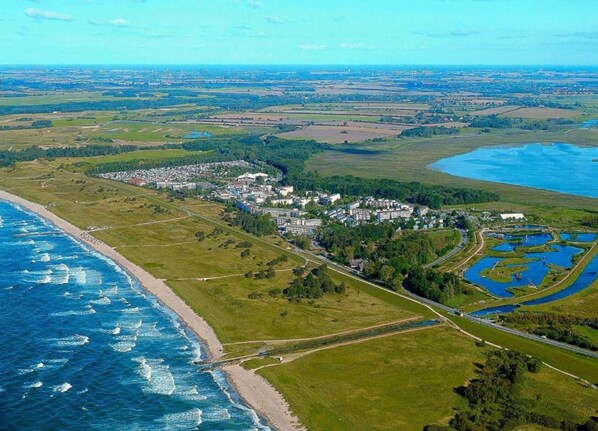 An aerial view of a coastal area with a residential complex, a beach, and a large body of water. - 4 Room Holiday Apartment with Garden near Lake (Lebrade)