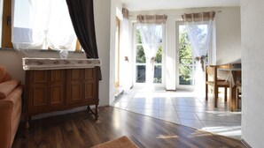 A room with a wooden cabinet, a table, and a window with curtains. - 4 Room Holiday Apartment with Garden near Lake (Lebrade)