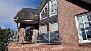 A two-story house with a balcony, brick walls, and multiple windows. - 4 Room Holiday Apartment with Garden near Lake (Lebrade)