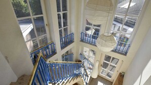 A multi-level interior with a blue staircase, large windows, and a hanging light fixture. - 4 Room Holiday Apartment with Garden near Lake (Lebrade)
