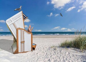 A beach chair with a person reclining, overlooking a sandy beach and ocean. - 4 Room Holiday Apartment with Garden near Lake (Lebrade)