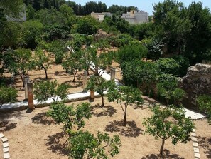 Un jardin agrémenté d’arbres et d’éléments architecturaux en pierre.