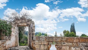 An ancient stone structure with a doorway, a white vase, and a stone wall. - Quaint Holiday Home in Lecce Apulia near Town Center (Casarano)
