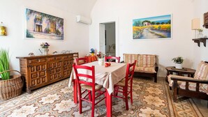 A dining area with a table set for four, surrounded by red chairs, a wooden cabinet, and a patterned floor. - Quaint Holiday Home in Lecce Apulia near Town Center (Casarano)