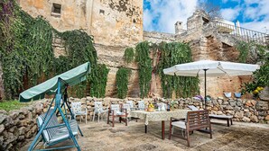 An outdoor seating area with stone walls, ivy, and a view of an old building. - Quaint Holiday Home in Lecce Apulia near Town Center (Casarano)