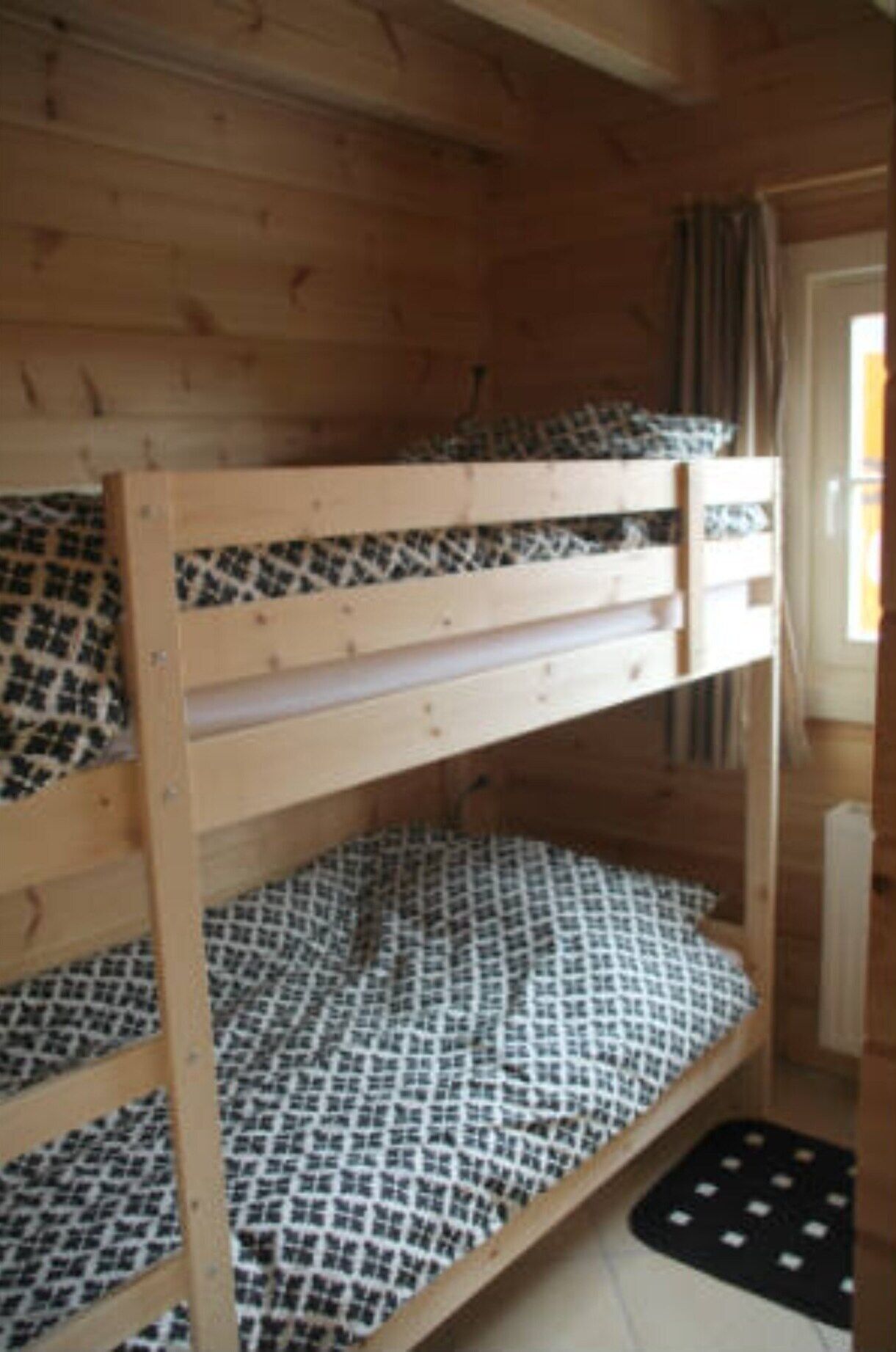 Un lit superposé avec une literie à motifs dans une chambre en bois.
