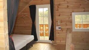 A small, cozy room with a single bed, wooden walls, and a window with a view of the outdoors. - Ferienhaus, Wissinghausen (Medebach)
