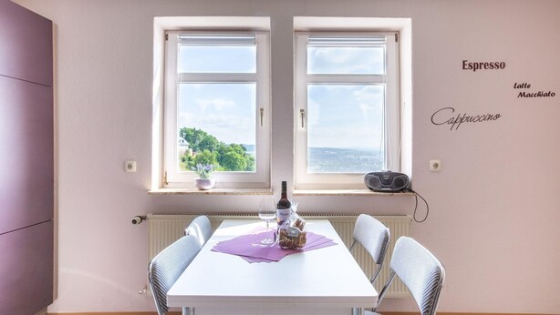 A dining area with a table set for two, a bottle of wine, and a basket of bread. - Heritage Apartment in Battenberg near Skiing (Battenberg)