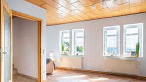 A spacious room with wooden flooring, large windows, and a view of the outdoors. - Heritage Apartment in Battenberg near Skiing (Battenberg)