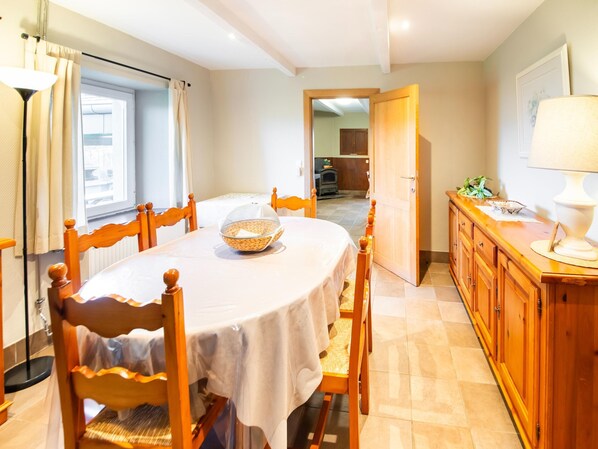 Un comedor con una mesa redonda, sillas y un armario de madera.