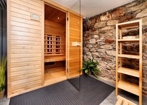 Un sauna en bois avec un mur en pierre, un banc en bois et une plante en pot.
