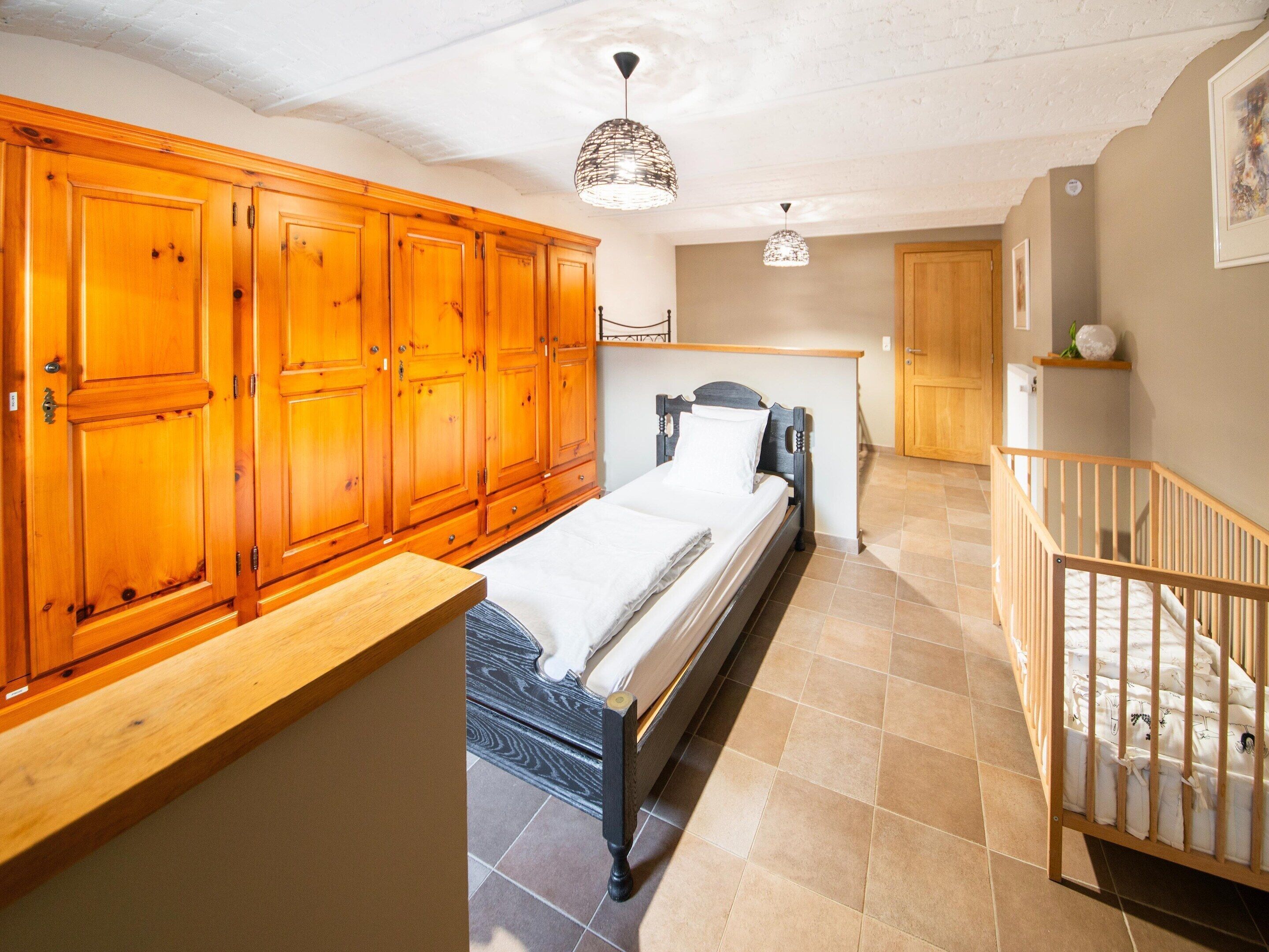 A bedroom with a bed, wooden wardrobe, and a staircase.