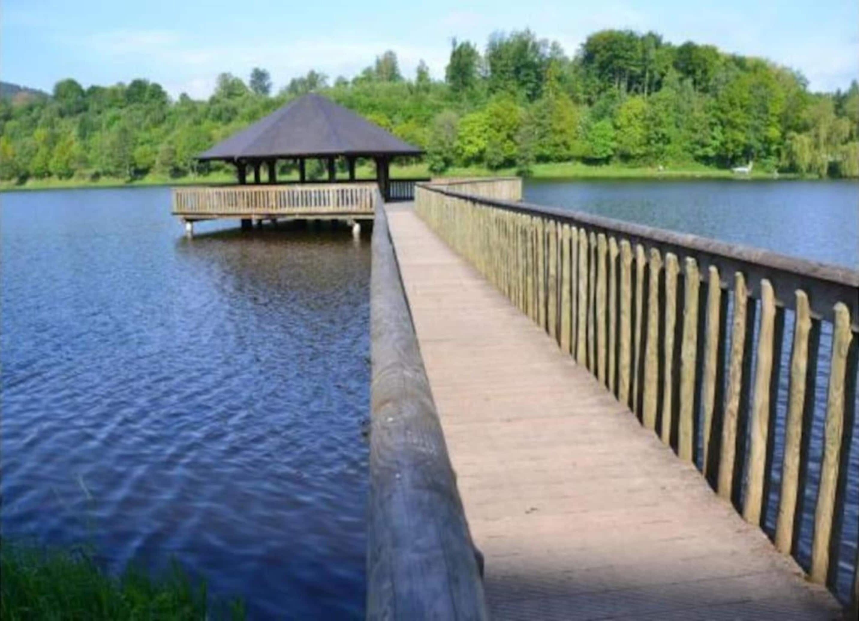Un molo di legno che si protende su un lago, con un gazebo all'estremità.