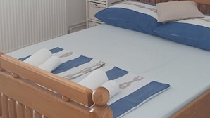 A bedroom with a wooden bed, white bedside tables, a radiator, and a wall-mounted air conditioner.