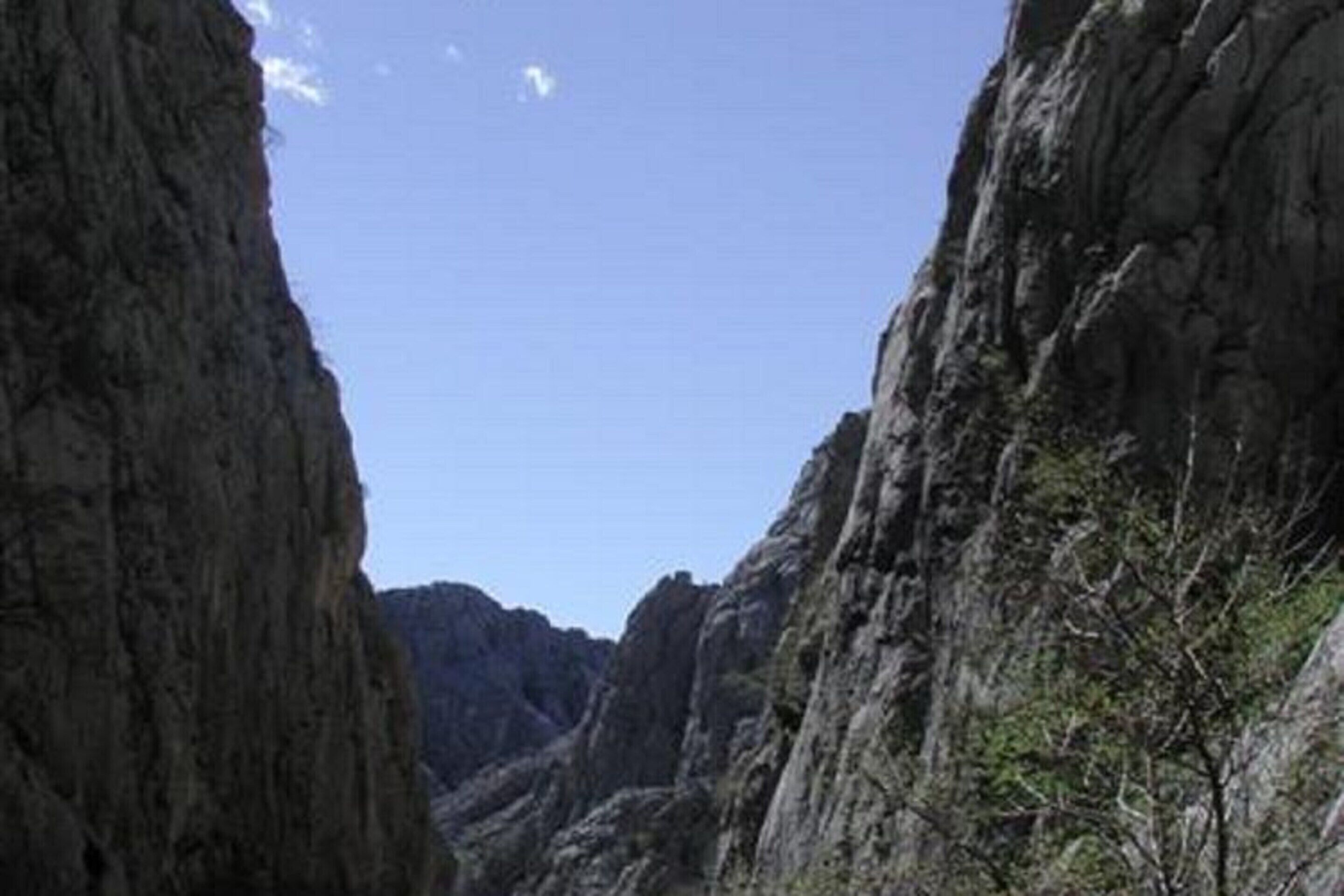 Eine schmale Schlucht mit steilen Felswänden und spärlicher Vegetation.