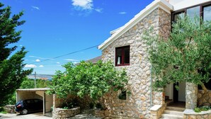 A stone house with a garage, a small window, and a staircase leading to the entrance.