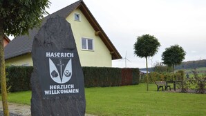 A stone sign with the text "HASERICH HERZLICH WILKOMMEN" in front of a house. - Ferienhaus Paula in Haserich im Hunsrueck (Haserich)