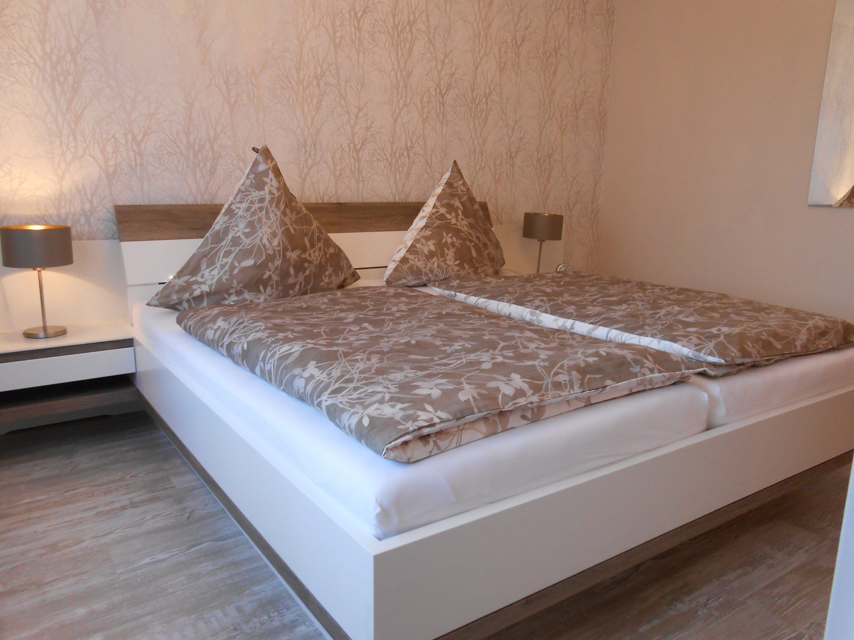 A neatly made bed with floral-patterned bedding and two decorative pillows.