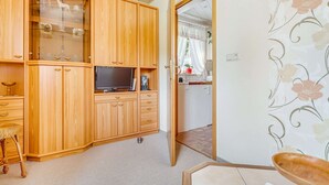 A room with wooden cabinets, a television, and a dining area with a table and chairs.