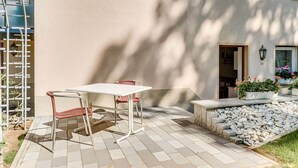 A patio with a table and chairs, a stone pathway, and potted plants.