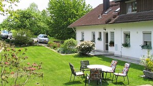 A white house with a tiled roof, a front porch with chairs, and a lawn. - Welcoming Chalet near Forest in Rohrnbach (Roehrnbach)
