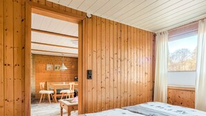 Une pièce de cabane en bois comprenant un lit, une table à manger, des chaises et un petit coin cuisine.