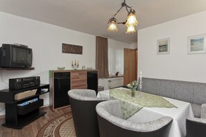 Cozy dining area with a table for two, comfortable chairs, and a mounted TV.