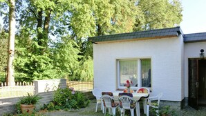A small white building with a window and a door, surrounded by a garden with a table and chairs. - Gartenwohnung in Ilsenburg (Ilsenburg)