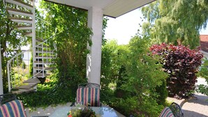 Un patio al aire libre con una mesa de vidrio, sillas a rayas y una escalera en espiral.
