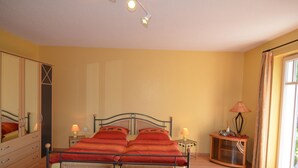 Un dormitorio con una cama, mesitas de noche, un espejo y una ventana.