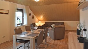Ein gemütliches Wohnzimmer mit Essbereich, Holzboden und einem großen Fenster.
