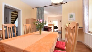 A dining area with a table set for four, wooden chairs, a vase with flowers, and a staircase in the background. - Quaint Apartment in Rerik near Sea (Rerik)