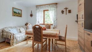 Una habitación acogedora con una mesa de comedor de madera, dos sillas, un sofá y un armario de madera.