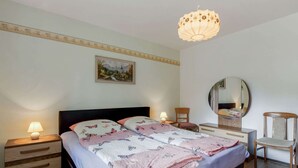 Un dormitorio con cama, mesitas de noche, un espejo y una lámpara colgante.