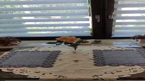 A table with a lace tablecloth, a vase with a single yellow flower, and a small potted plant. - Apartment in Wehlen by Moselle Vineyards (Bernkastel-Kues)
