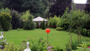 A garden with a lawn, various plants, and a white gazebo in the background. - Flat in Bellenberg With Sunbathing Lawn (Horn-Bad Meinberg)