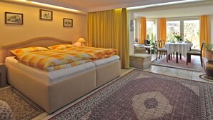 A hotel room with a large bed, a dining area with a table and chairs, and a view of the outdoors. - Flat in Bellenberg With Sunbathing Lawn (Horn-Bad Meinberg)
