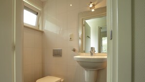 A bathroom with a toilet, a sink, a mirror, and a window. - Holiday Home in Kortgene Near Lake Veere (Kortgene)